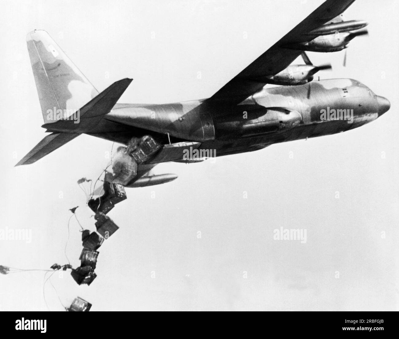 Vietnam: 1967 A USA Air Force C-130 Hercules sale bruscamente mentre rilascia il suo enorme carico di rifornimenti in un'importante caduta di paracadute. Foto Stock