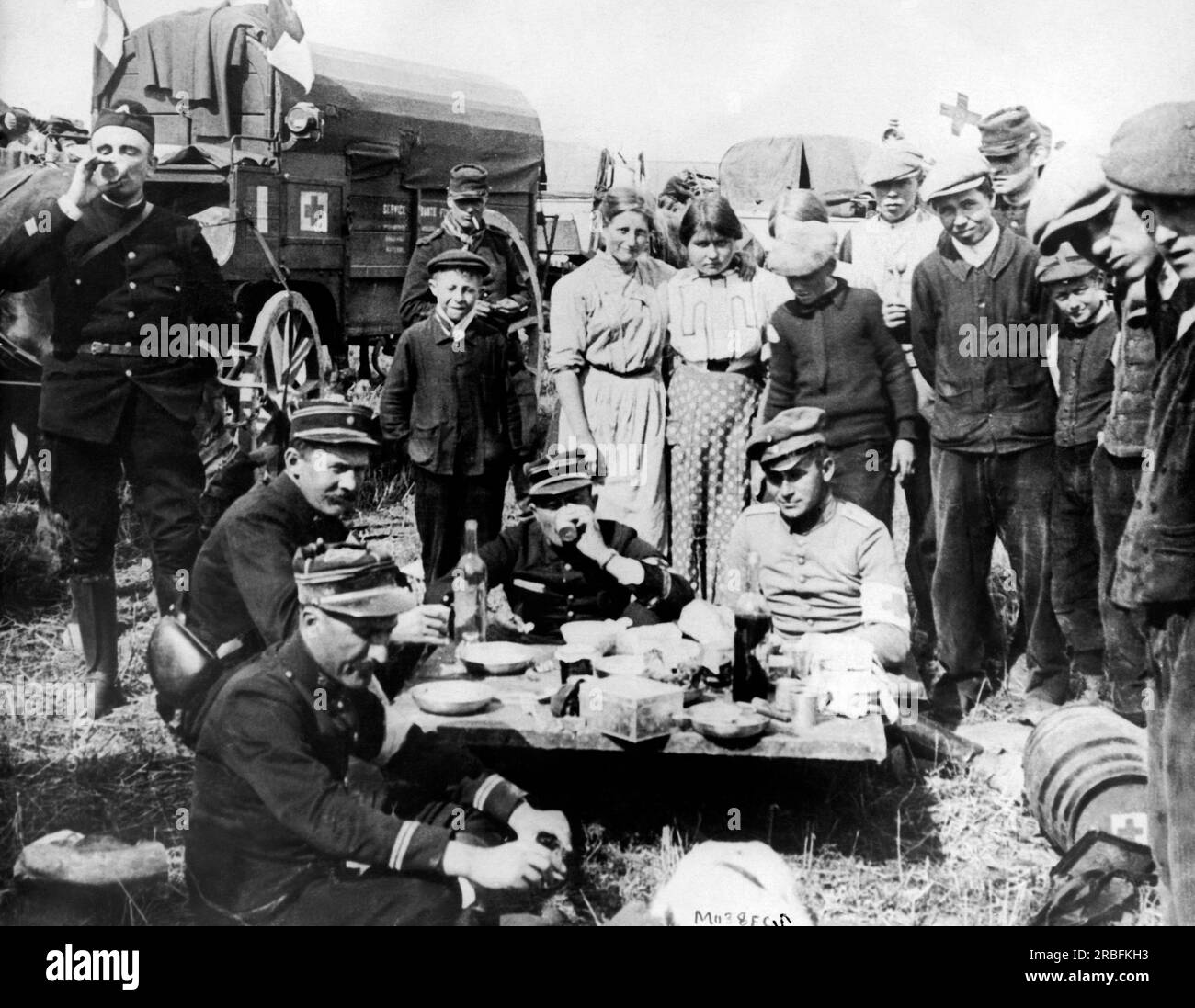 Argonne Forest, Francia: Novembre 1918 ufficiali francesi di una divisione ambulanza cenano sul lato della strada con un prigioniero della Croce Rossa tedesca caduto nelle loro mani. Un gruppo di spettatori interessati si è riunito in giro. Foto Stock