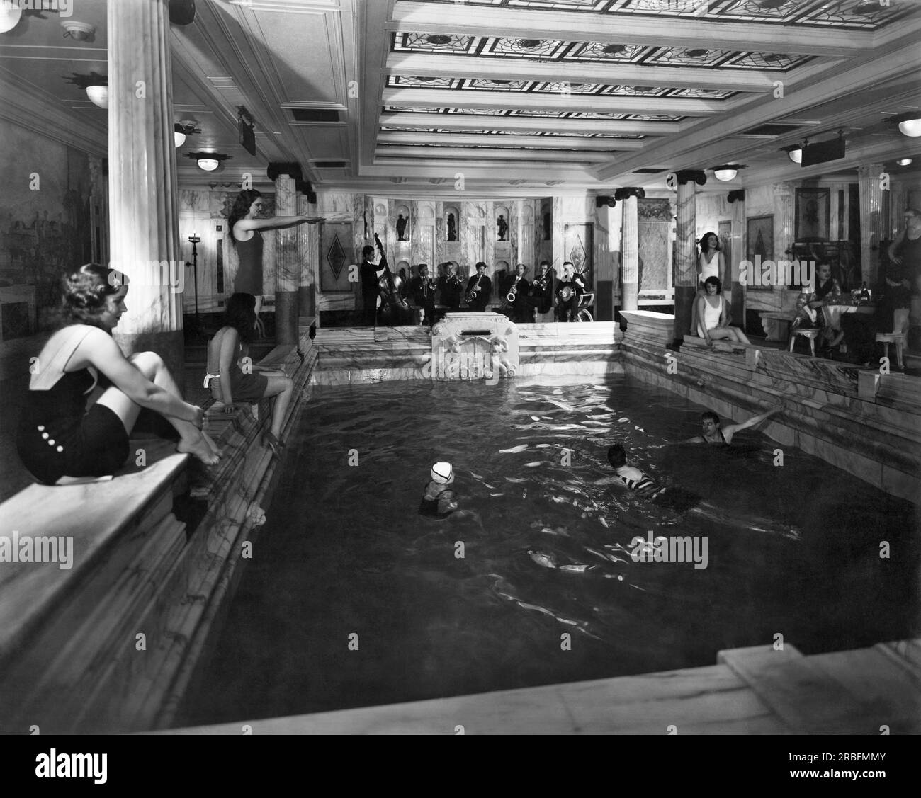 Italia: circa 1927 passeggeri di prima classe che si rilassano intorno alla loro piscina coperta con una jazz band sul transatlantico italiano Vulcania Foto Stock