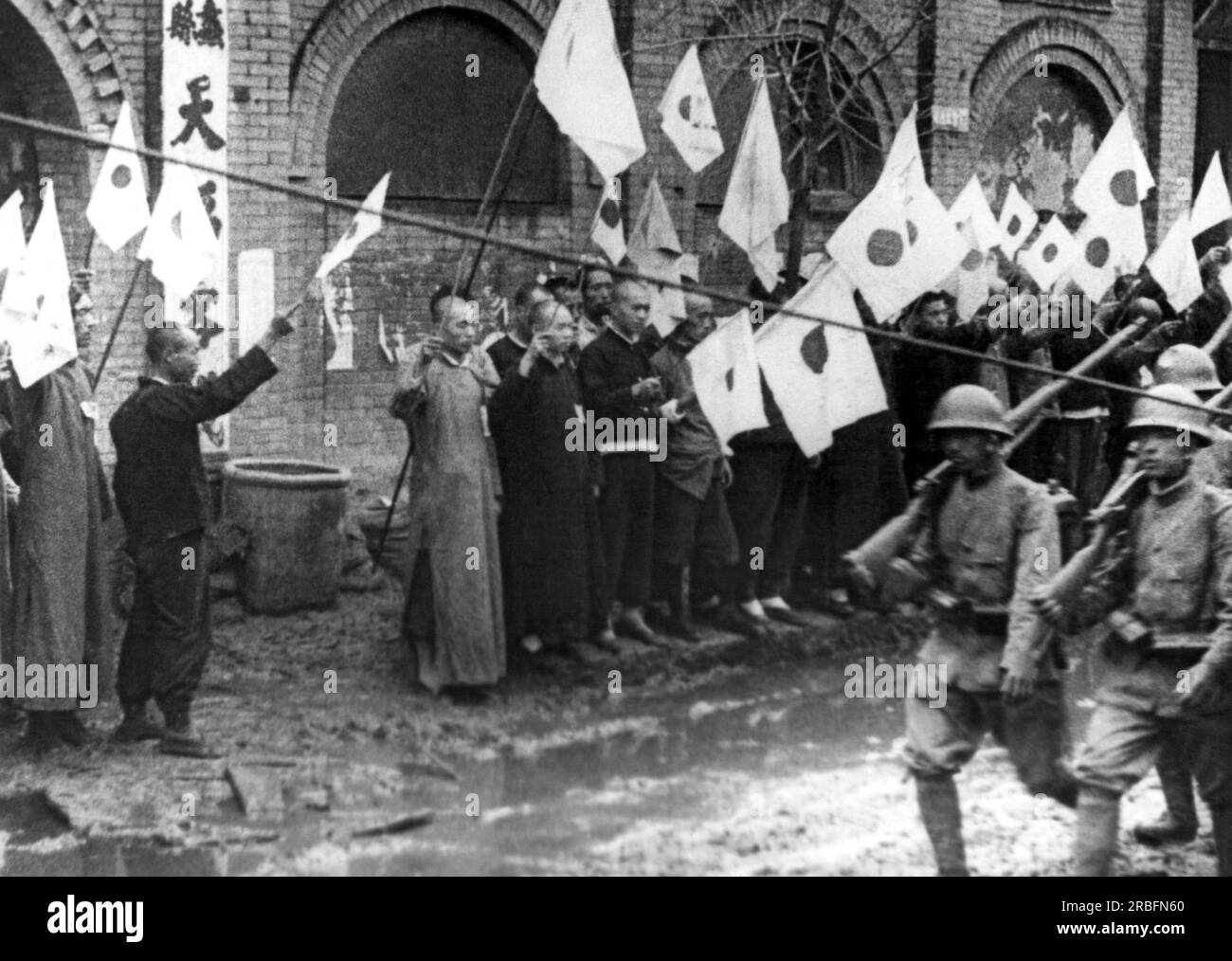 Fronte della Cina settentrionale: c. 1938. Le truppe giapponesi vengono accolte dai residenti cinesi con bandiere mentre guidano verso ovest da Tienstin verso Pao-ting, la capitale di Mopei. Foto Stock