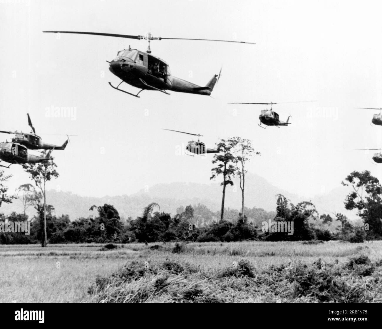 Vietnam: 1967 circa Un volo di Hueys si sposta nella zona di sbarco per sbarcare le sue truppe. Ognuno salta in meno di sei secondi mentre le truppe colpiscono il terreno correndo e spariscono tra gli alberi. Foto Stock