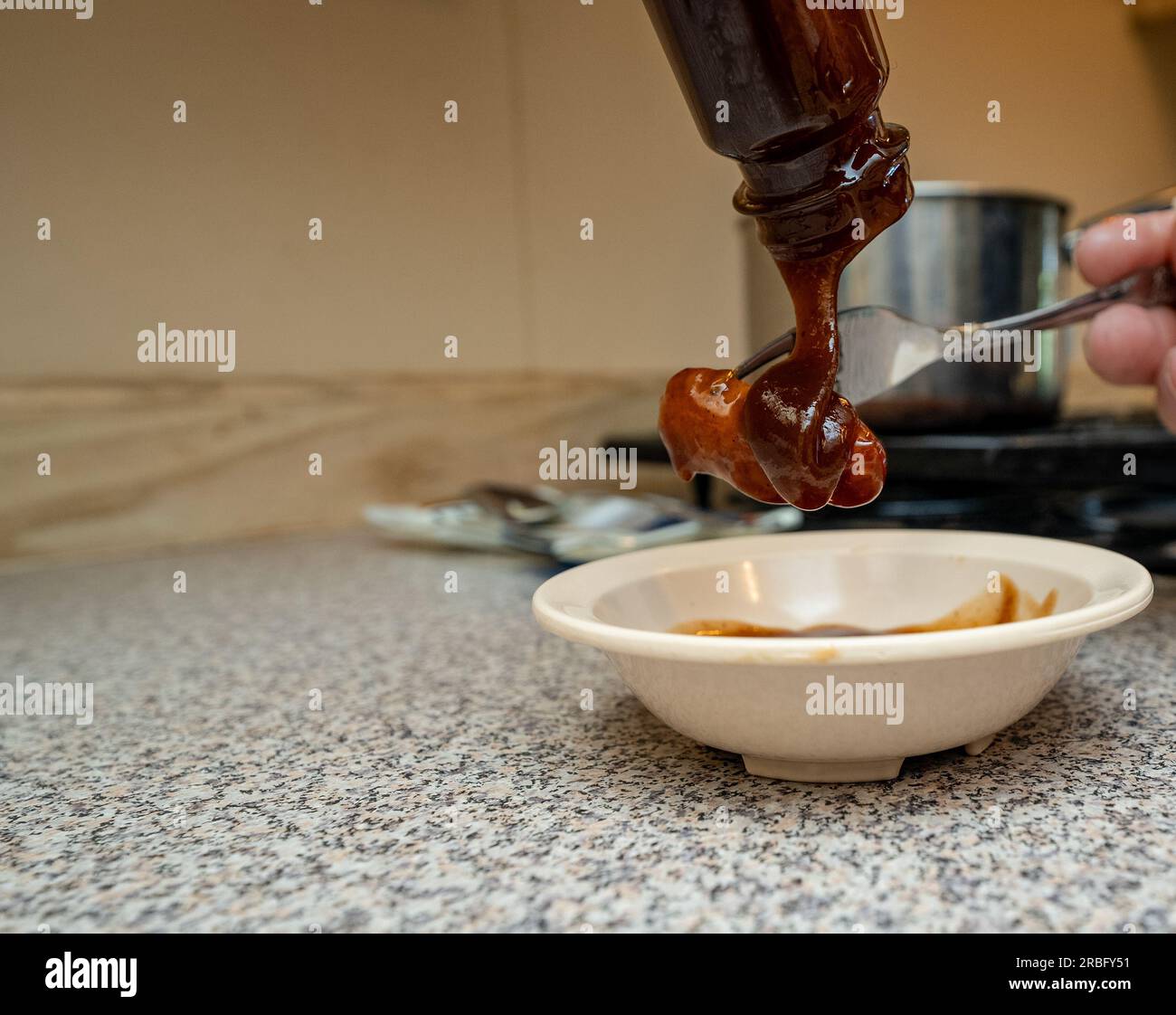 Versare salsa barbecue su Smokie Foto Stock