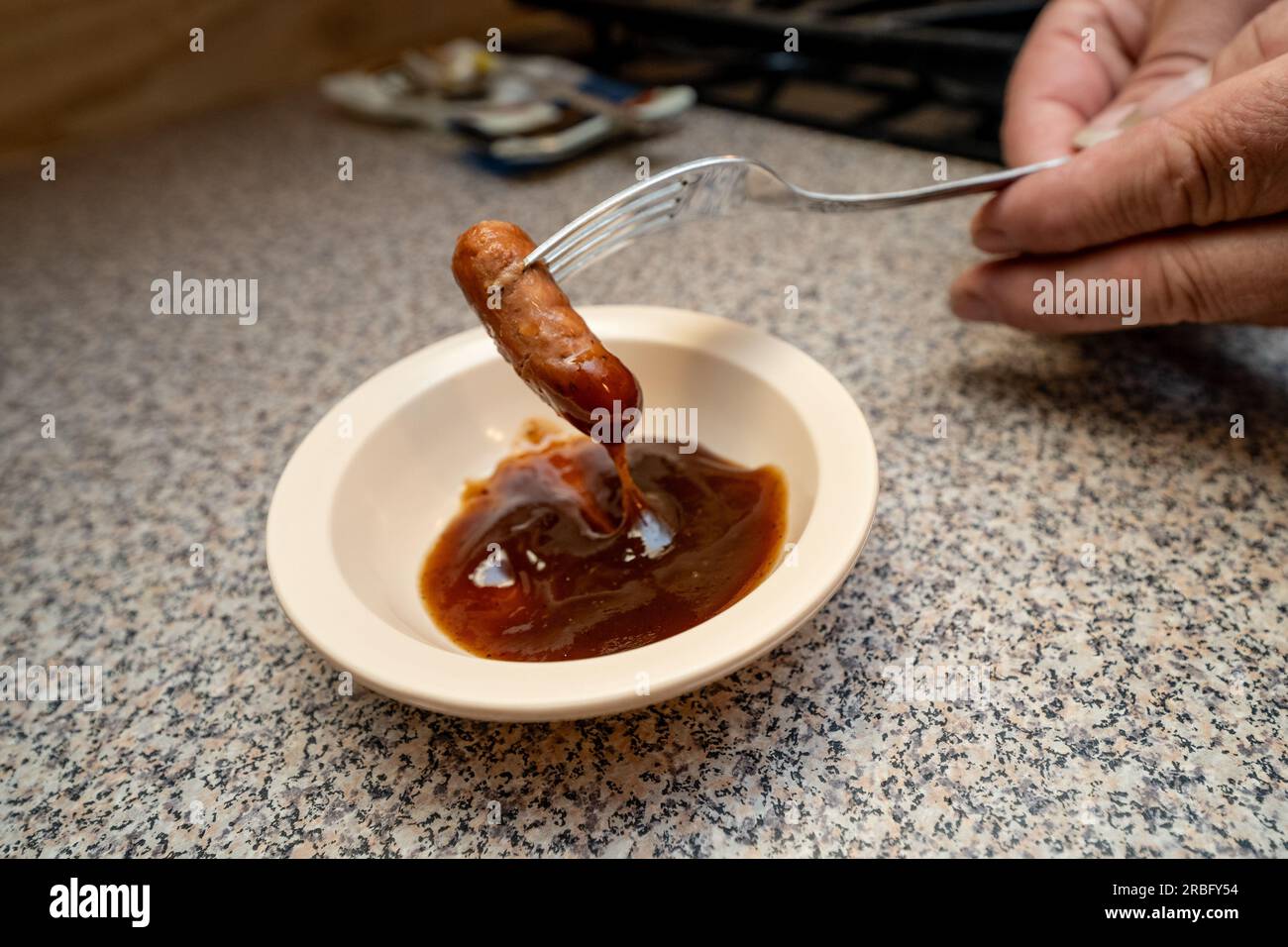 Immergere lo Smokie nella salsa barbecue Foto Stock