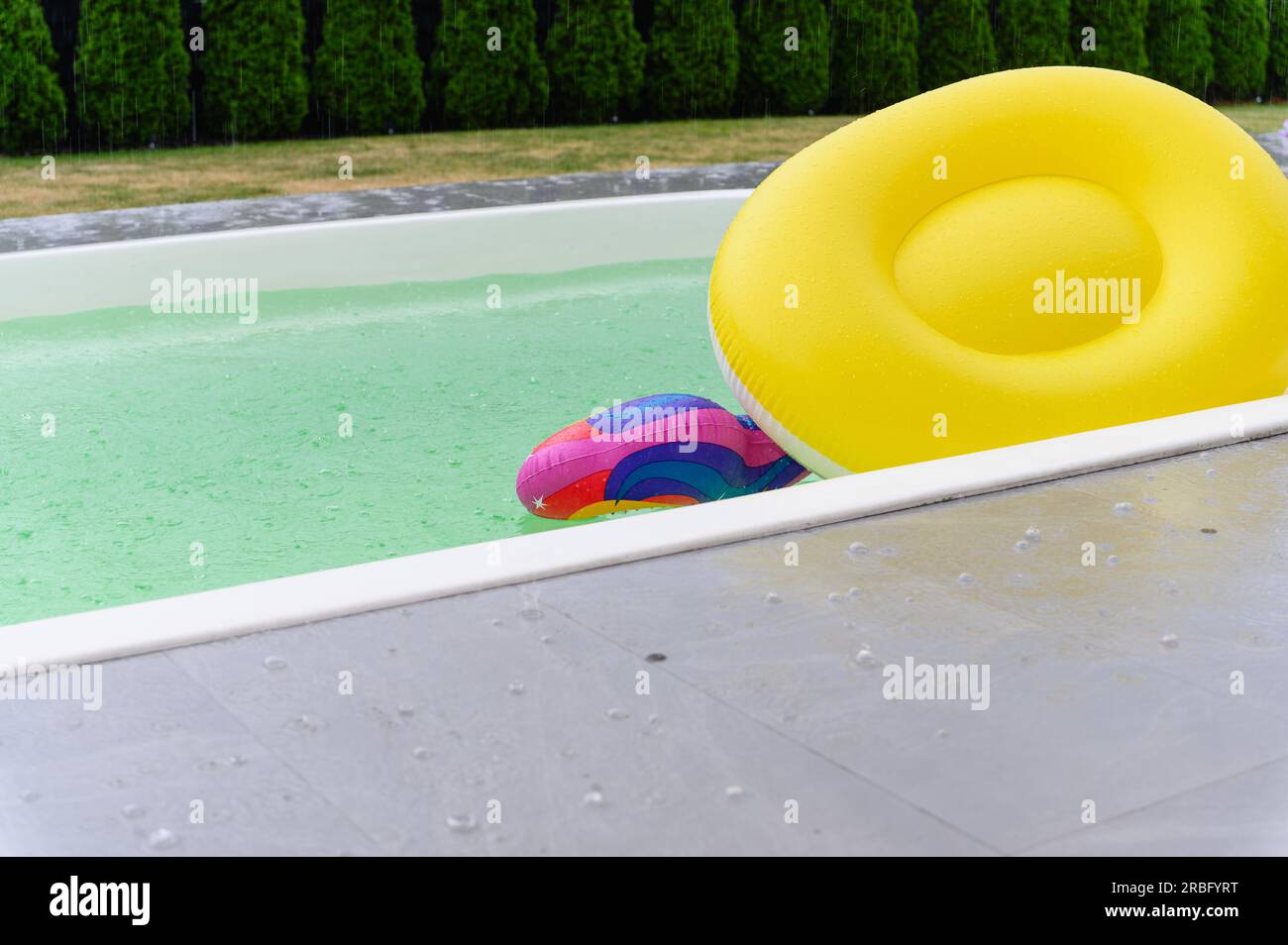 Le gocce di pioggia cadono sulla superficie della piscina. Pioggia battente. Foto Stock