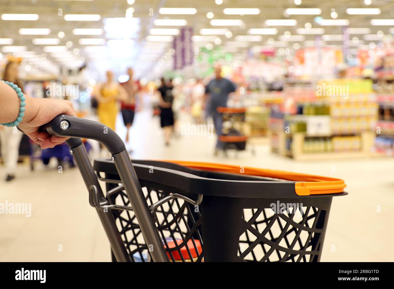 Carrello in mano femminile in un supermercato. Clienti durante la vendita Foto Stock