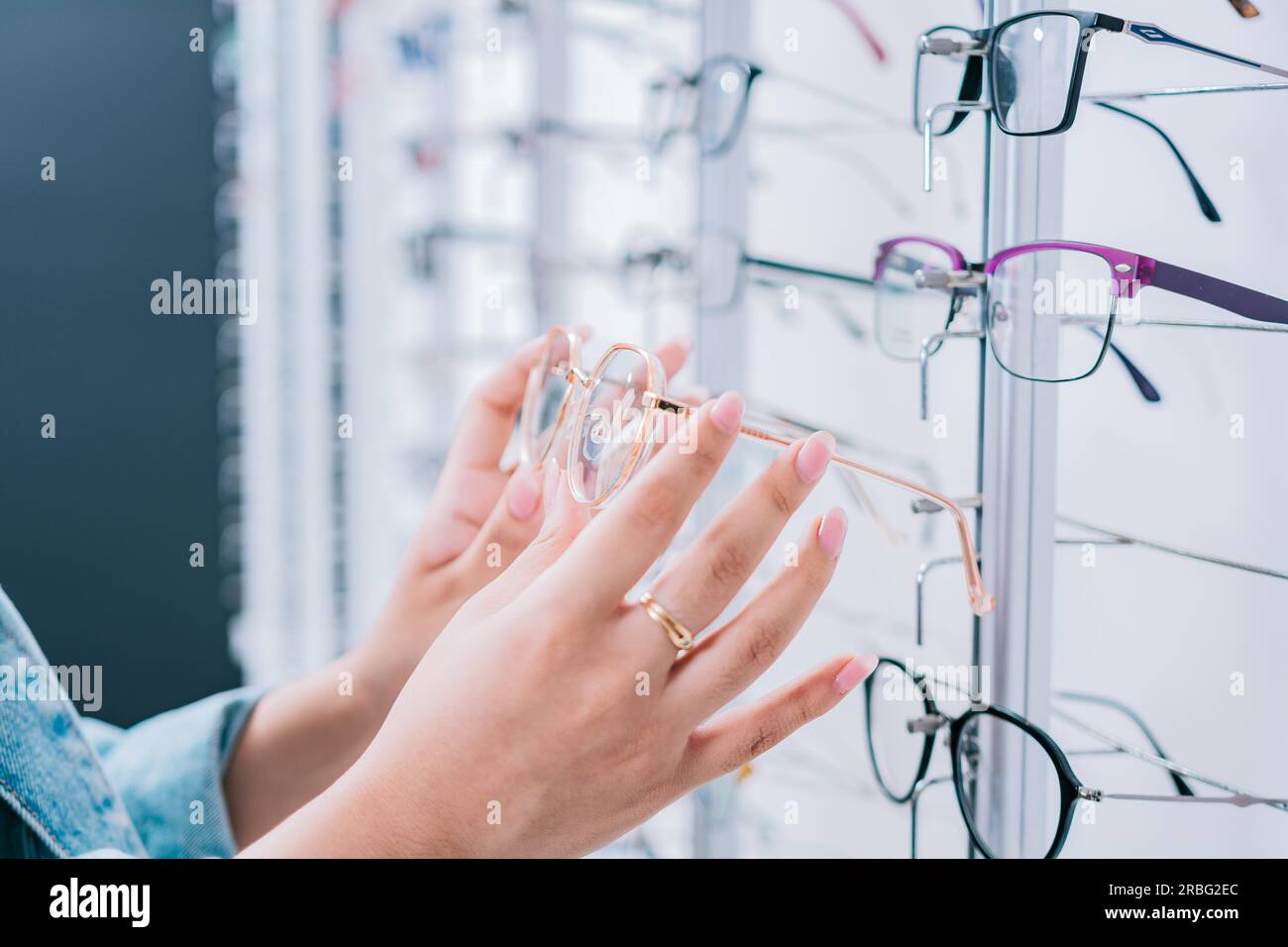 Acquirente donna che sceglie gli occhiali in un negozio. Cliente femminile che sceglie gli occhiali in un negozio di ottica, Girl Hands sceglie gli occhiali in un negozio Foto Stock