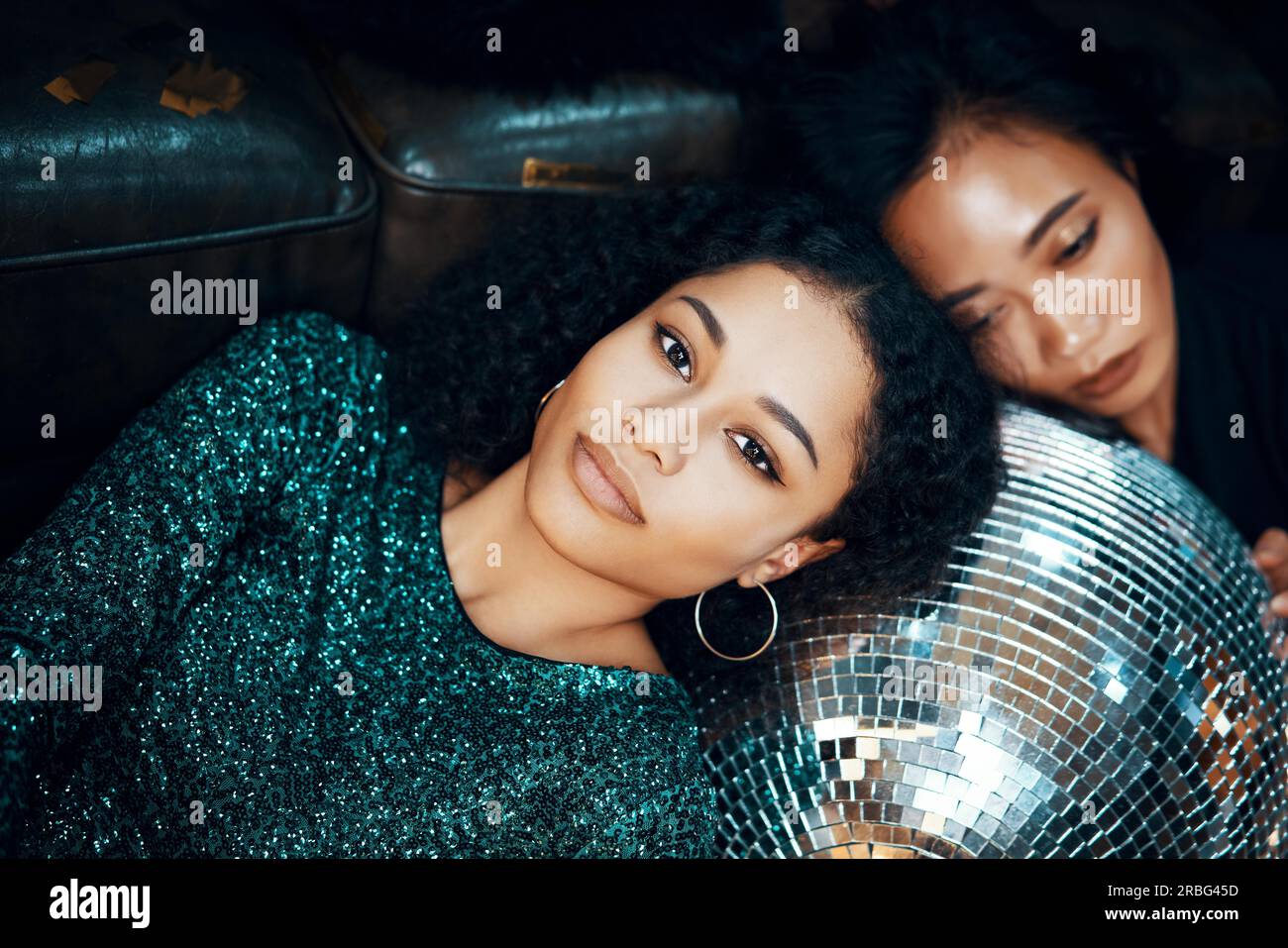 Una giovane donna africana che si rilassa e si sdraiata sul pavimento per un ballo da discoteca in un nightclub dopo una festa pazzesca. Capodanno, compleanno, festività, divertimento Foto Stock