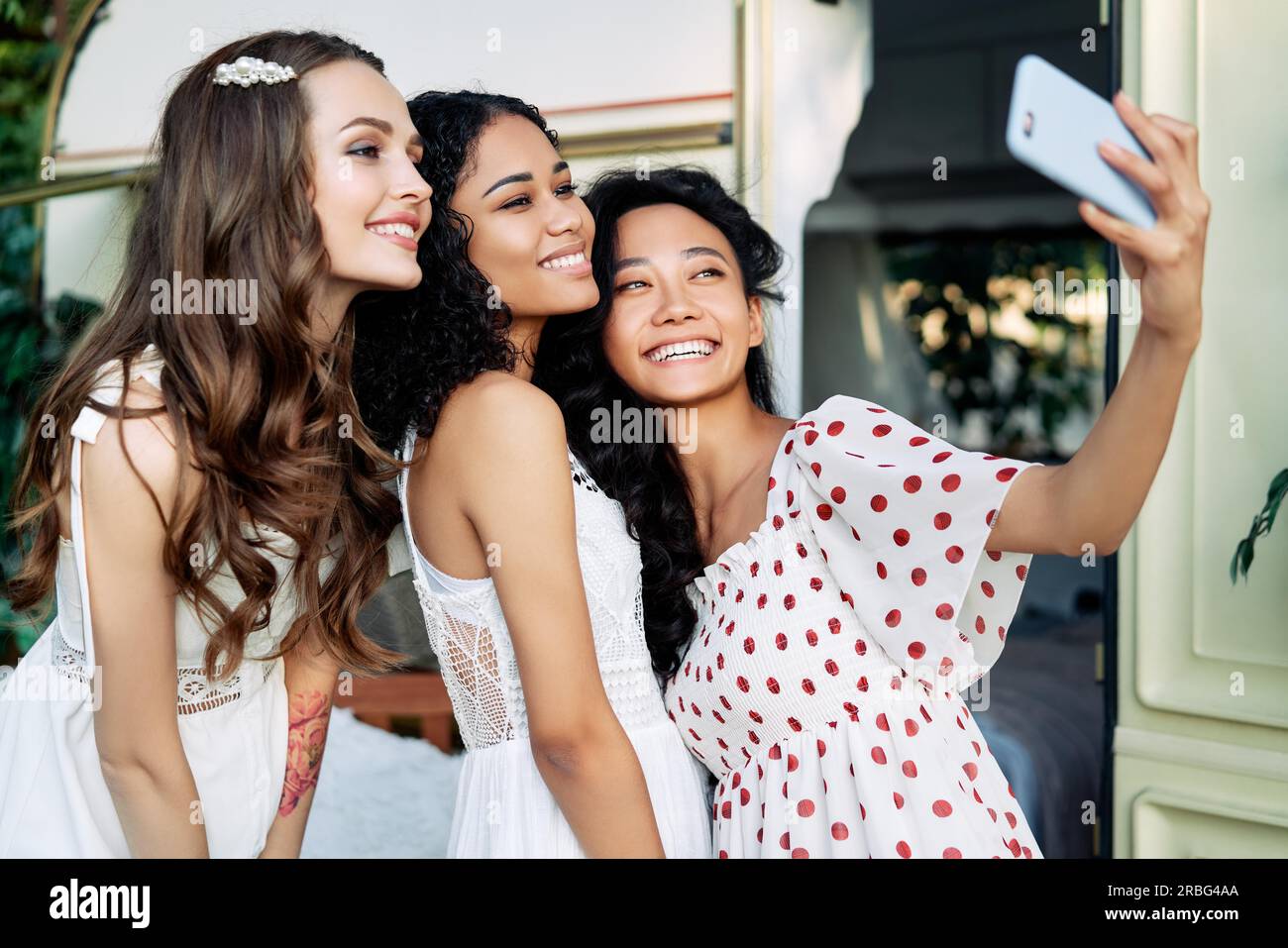 Bella donna sorridente tenendo selfie con il telefono cellulare. Multi etnico caucasico ragazze, africane americane ed asiatiche femmine rendendo self portrait durante Foto Stock