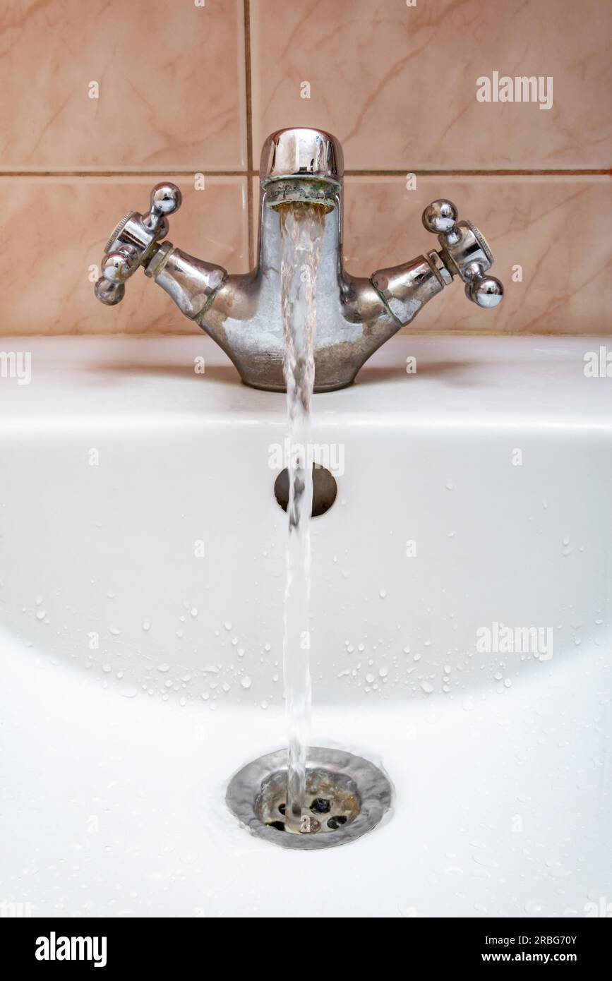 L'immagine verticale di un rubinetto con acqua fluente fortemente sotto pressione elevata Foto Stock