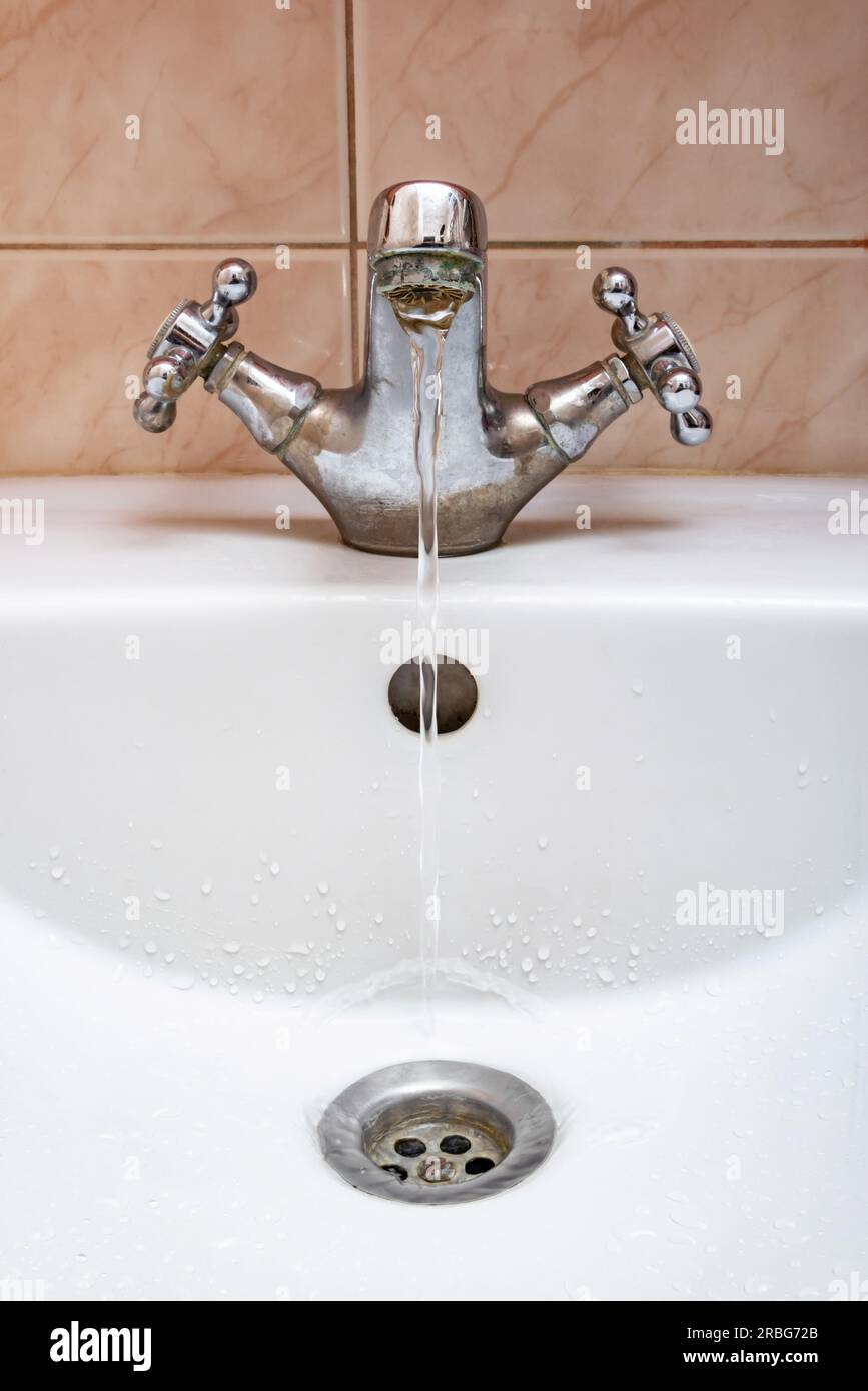 L'immagine verticale di un rubinetto con acqua che scorre lentamente durante un periodo di penuria Foto Stock