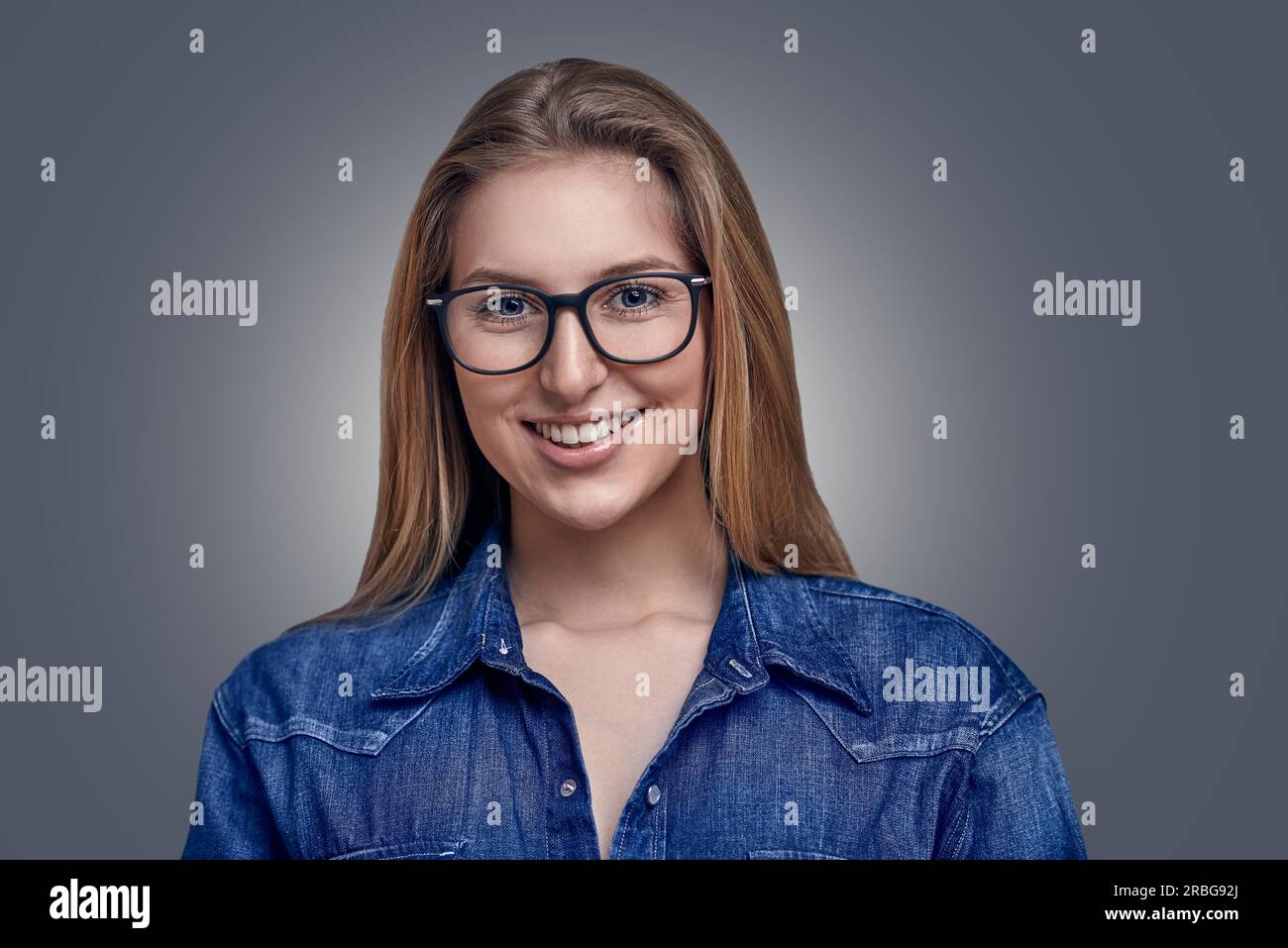 Elegante Attraente donna bionda con i capelli in un panino con gli occhiali a sorridere alla telecamera Foto Stock