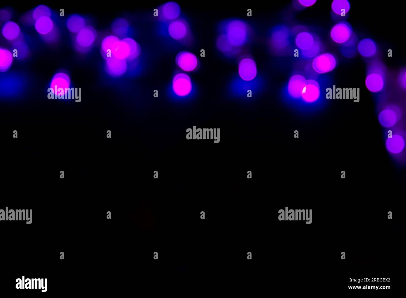 Luci bokeh astratte viola natalizie su sfondo scuro con spazio di copia per testo o design. Sfondo astratto con bokeh viola. Foto Stock