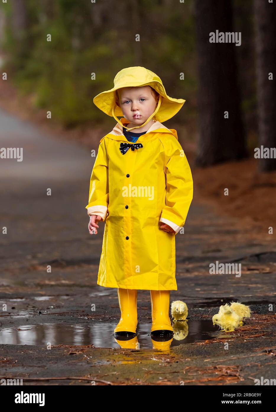 Un bambino gioca sotto la pioggia, mentre i piccoli cercano di bere un drink d'acqua Foto Stock