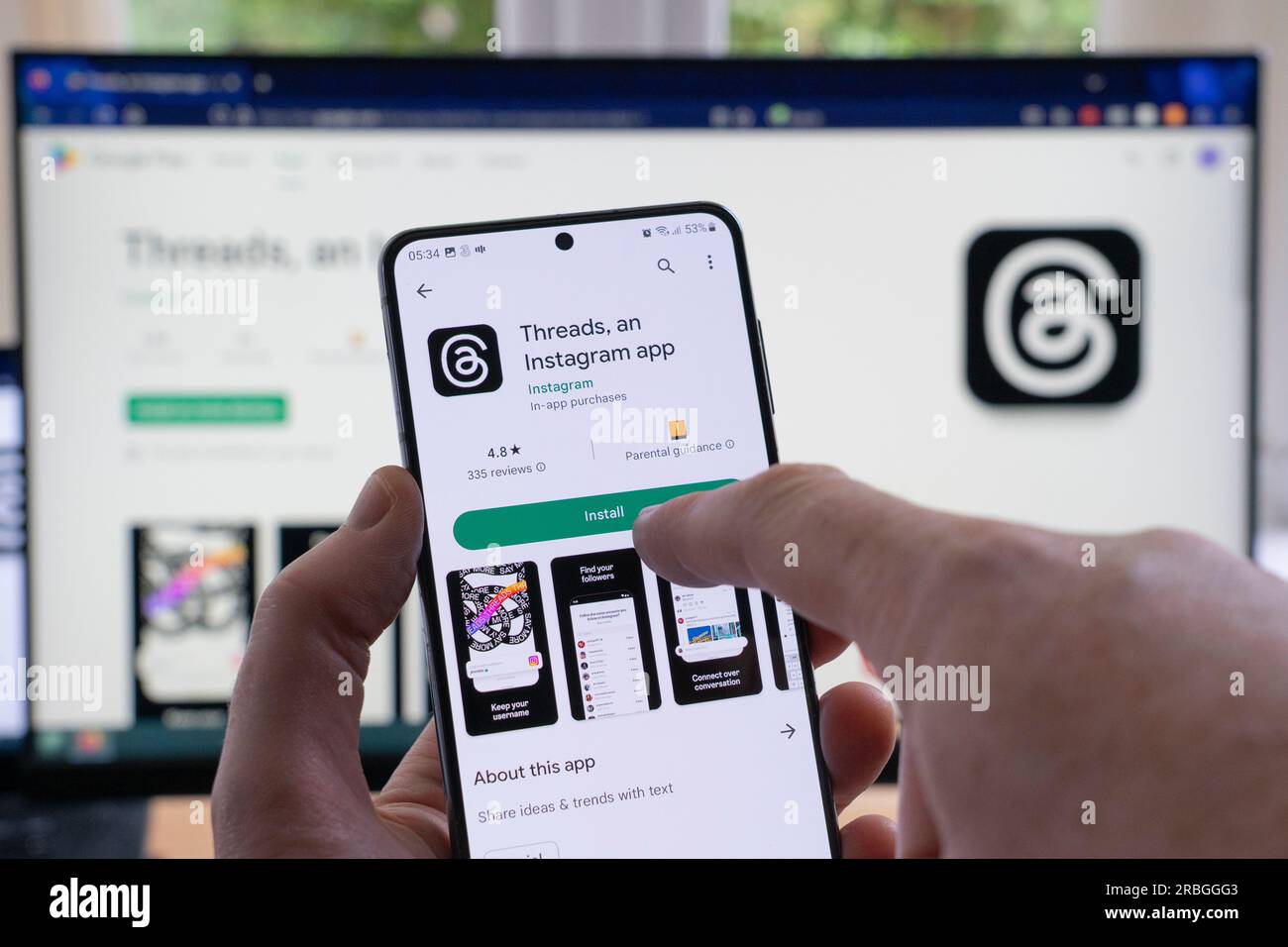 Mano dell'uomo che tiene in mano uno smartphone che visualizza la schermata di download e installazione di Google Play per i thread e il relativo logo, un'app Instagram di Meta. REGNO UNITO Foto Stock