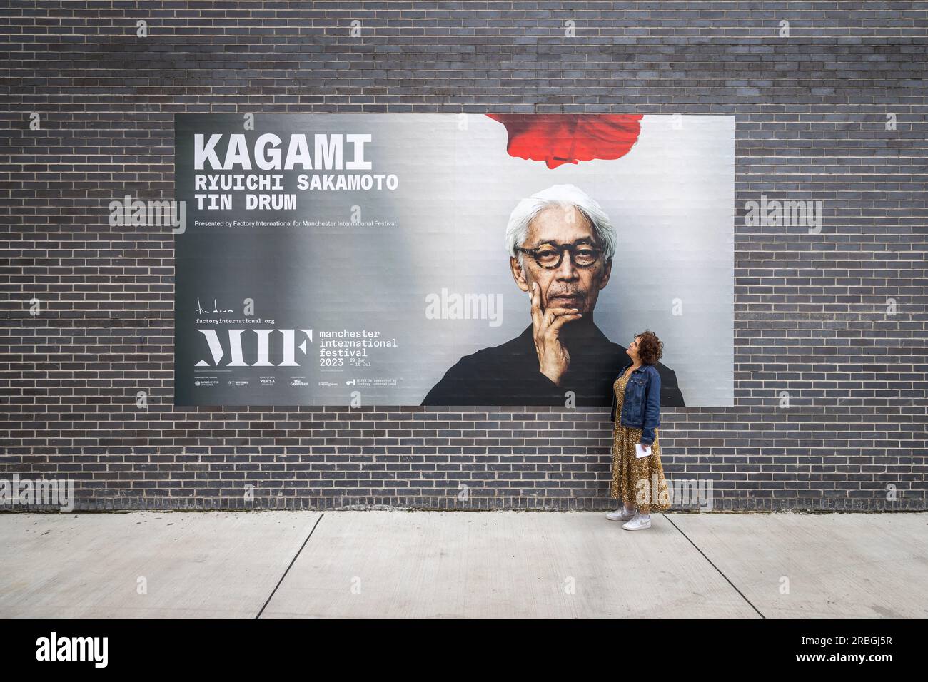 Affascinato dal genio di Ryuichi Sakamoto, un fan devoto guarda su un cartellone che promuove Kagami, un'esperienza di concerto virtuale rivoluzionaria. Foto Stock