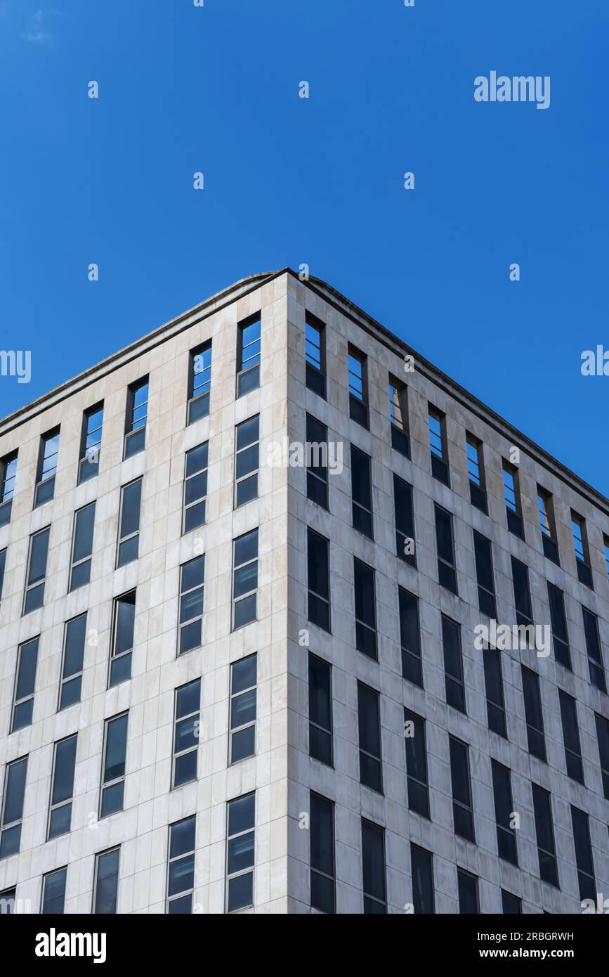 facciate angolari di un edificio per uffici con piastrelle di marmo e molte piccole finestre strette in una giornata con cielo blu cristallino Foto Stock