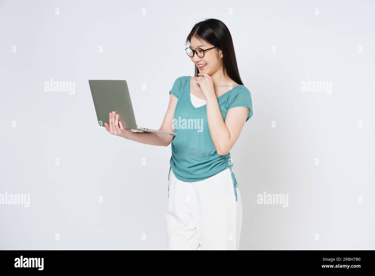 Giovane donna che tiene in mano un notebook mentre è isolata su sfondo bianco. Foto Stock