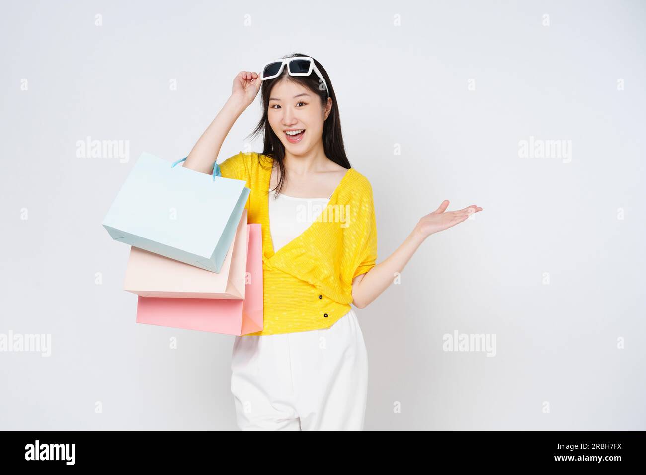 Giovane donna felice che tiene borse della spesa isolate su sfondo bianco. Foto Stock