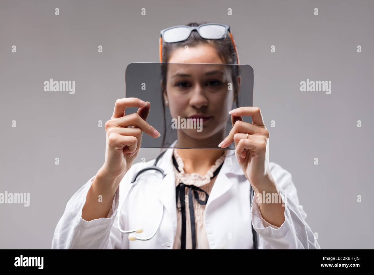 Una medico di sesso femminile analizza I dati COPYSPACE su un tablet digitale. Il futuristico schermo trasparente è vuoto per il tuo input. Occhiali indossati come archetto, Foto Stock