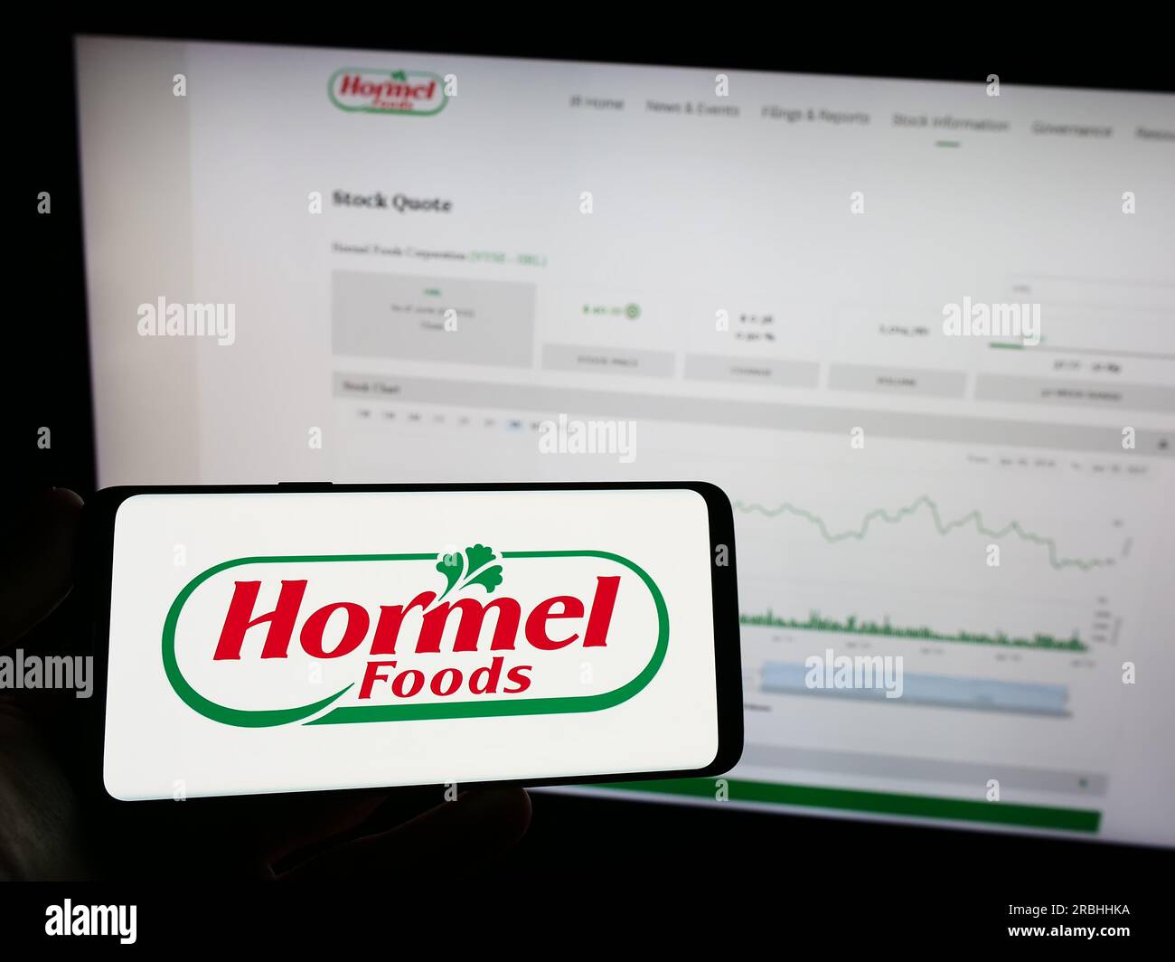 Persona che tiene il telefono cellulare con il logo della società alimentare americana Hormel Foods Corporation sullo schermo davanti alla pagina Web. Concentrarsi sul display del telefono. Foto Stock