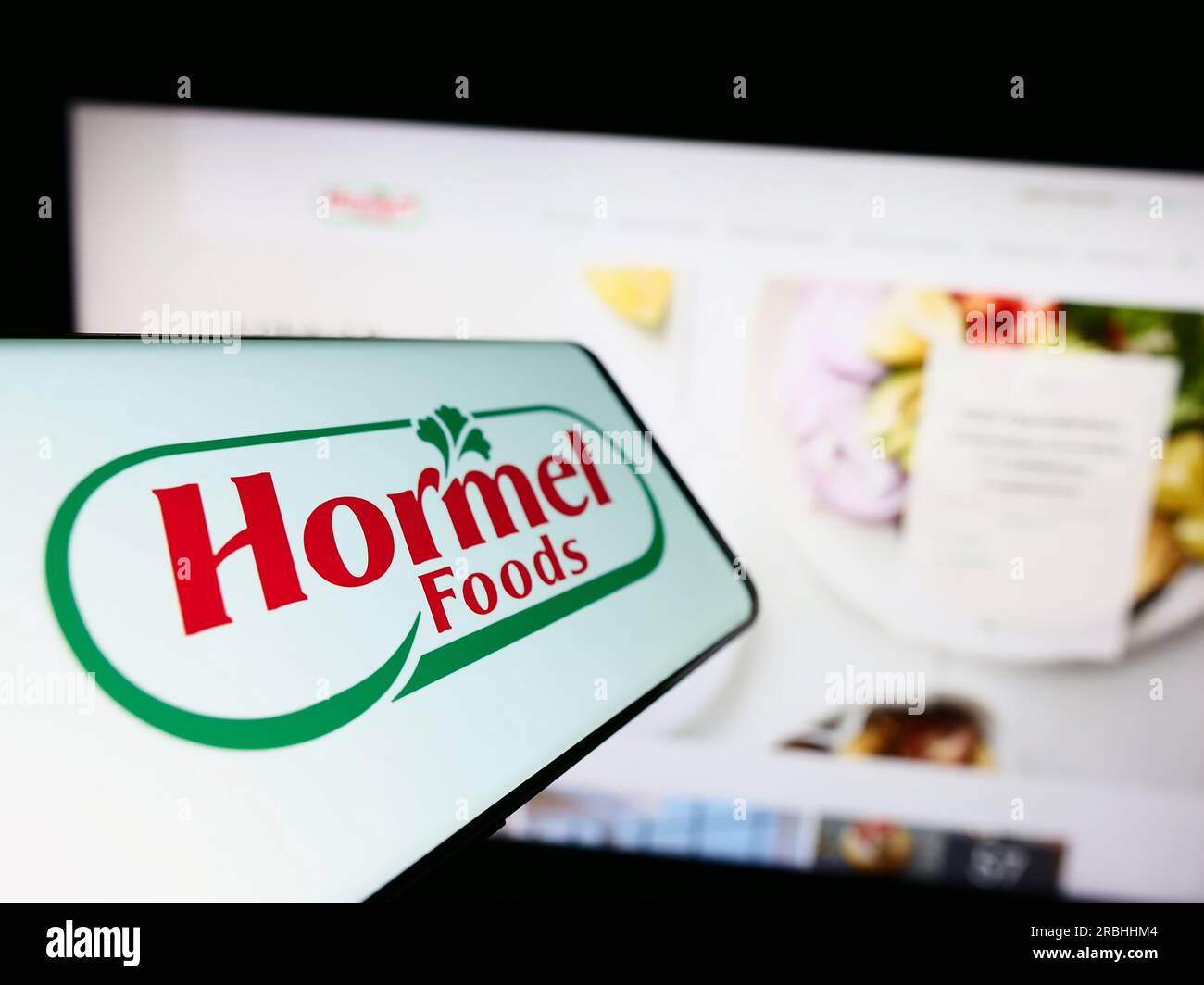 Smartphone con il logo dell'azienda alimentare americana Hormel Foods Corporation sullo schermo di fronte al sito Web. Mettere a fuoco il display centrale sinistro del telefono. Foto Stock