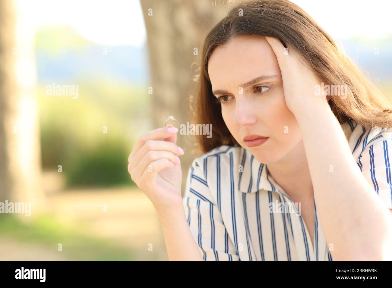 Fidanzata preoccupata che guarda l'anello di fidanzamento in natura Foto Stock