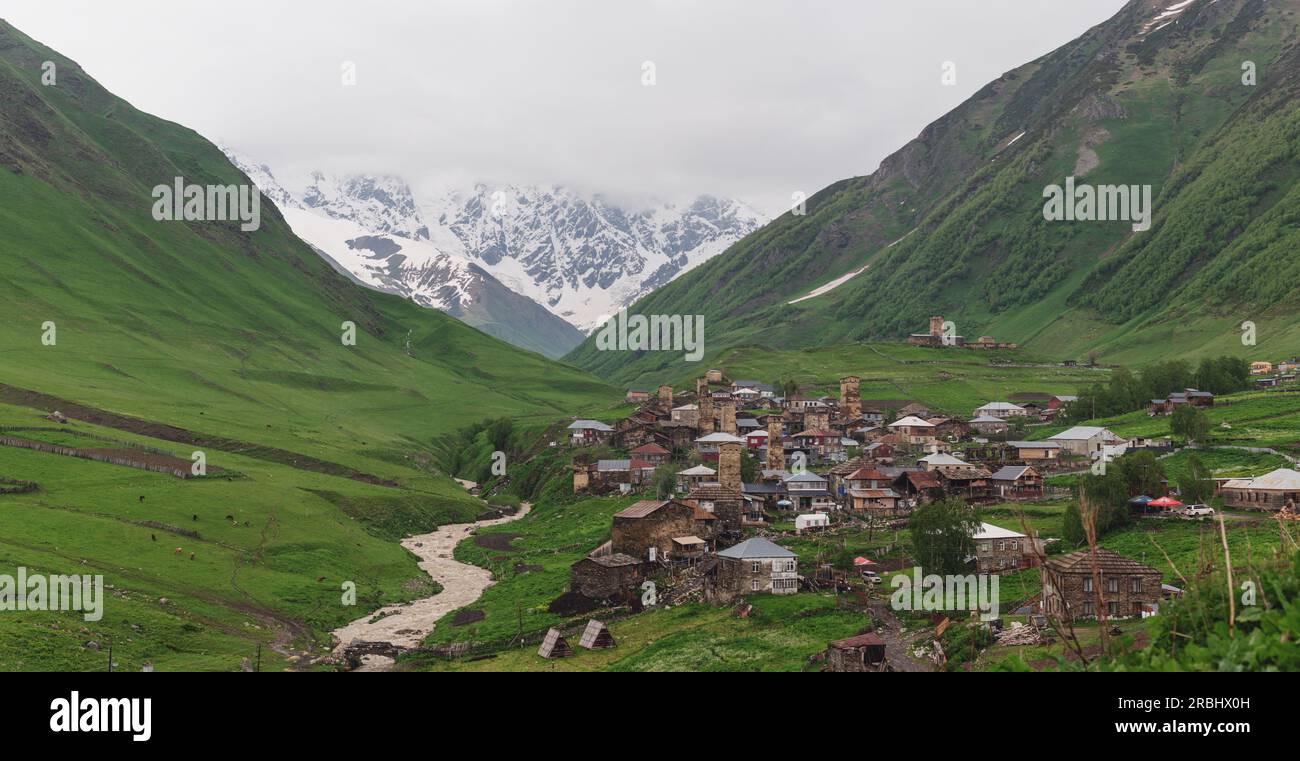 Villaggio Ushguli sulle montagne in Georgia. Montagne innevate e verdi colline paesaggistiche in estate Foto Stock