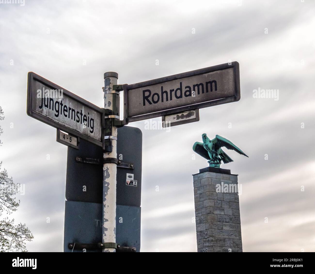 Cartello stradale all'angolo tra Rohrdamm & Jungfernsteig & Bronze Imperial Eagle al Siemens War Memorial, Siemensstadt, Spandau, Berlino Foto Stock