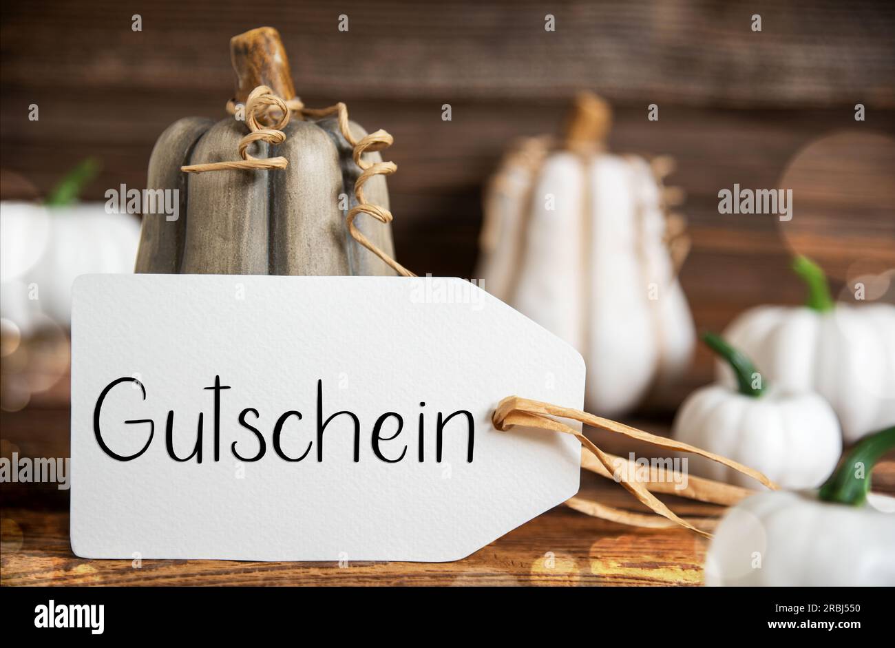 Decorazioni autunnali con zucche, decorazioni autunnali rustiche con etichetta con testo tedesco Gutschein, che significa voucher in inglese Foto Stock