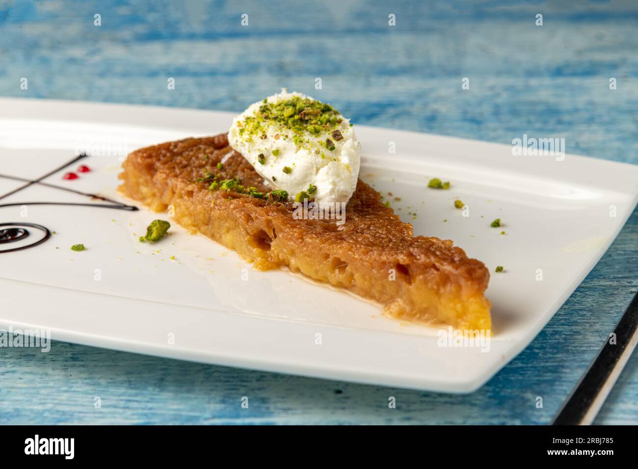 Dessert turco ekmek kadayifi con crema di latte e pistacchio su un piatto di porcellana bianca Foto Stock