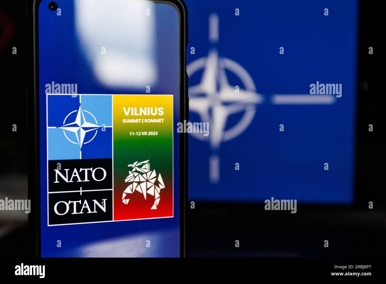 Vilnius, Lituania - 2023 luglio 10: Vertice della NATO Logo di Vilnius sullo schermo e bandiera della NATO. Foto di alta qualità Foto Stock