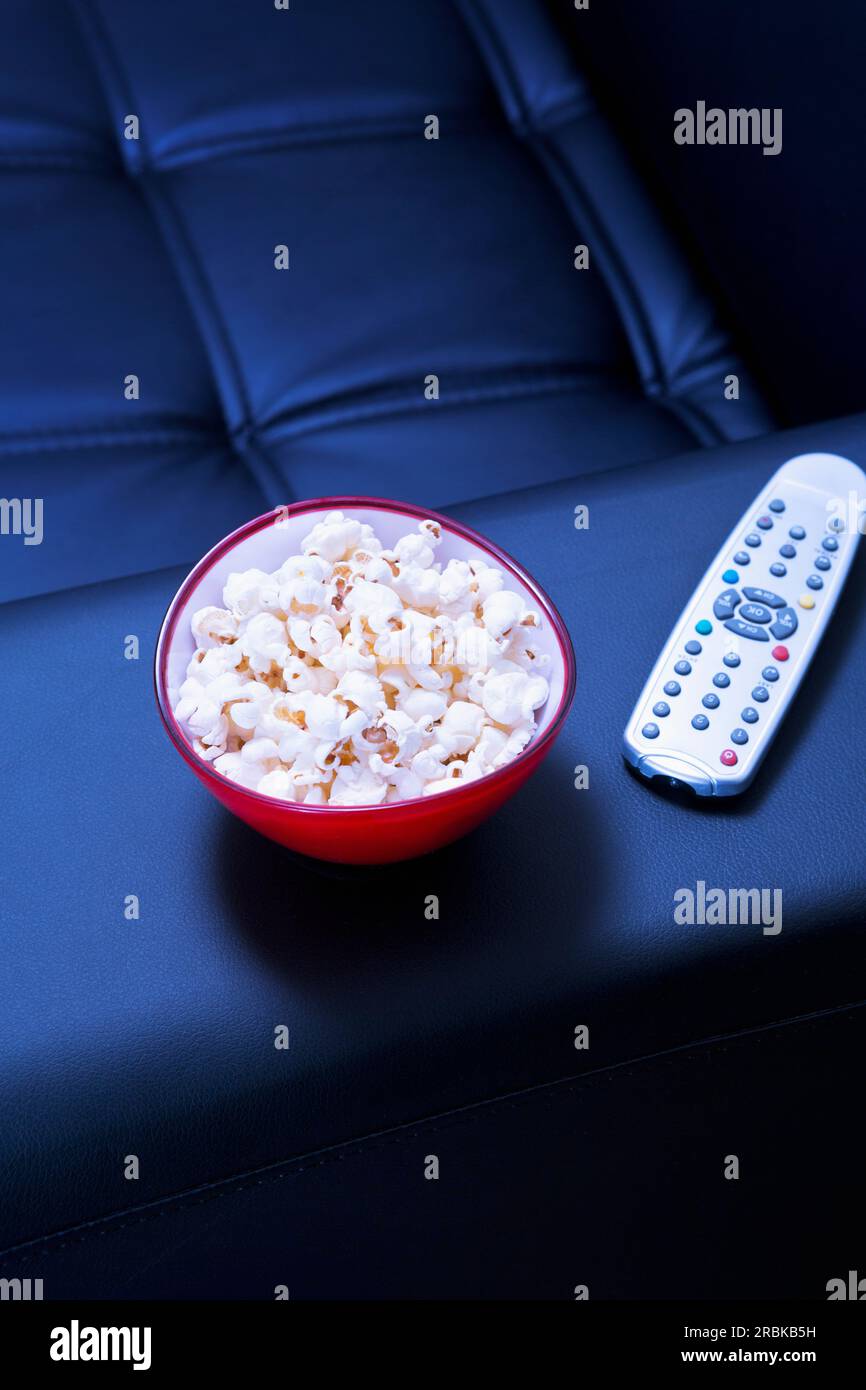 Ciotola di popcorn sul divano nero la sera Foto Stock