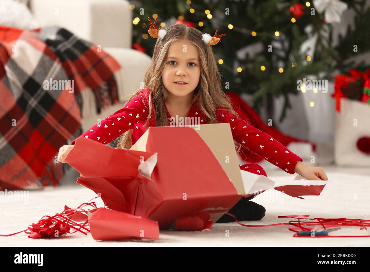 Simpatica bambina che scarta il regalo di Natale a casa Foto stock - Alamy