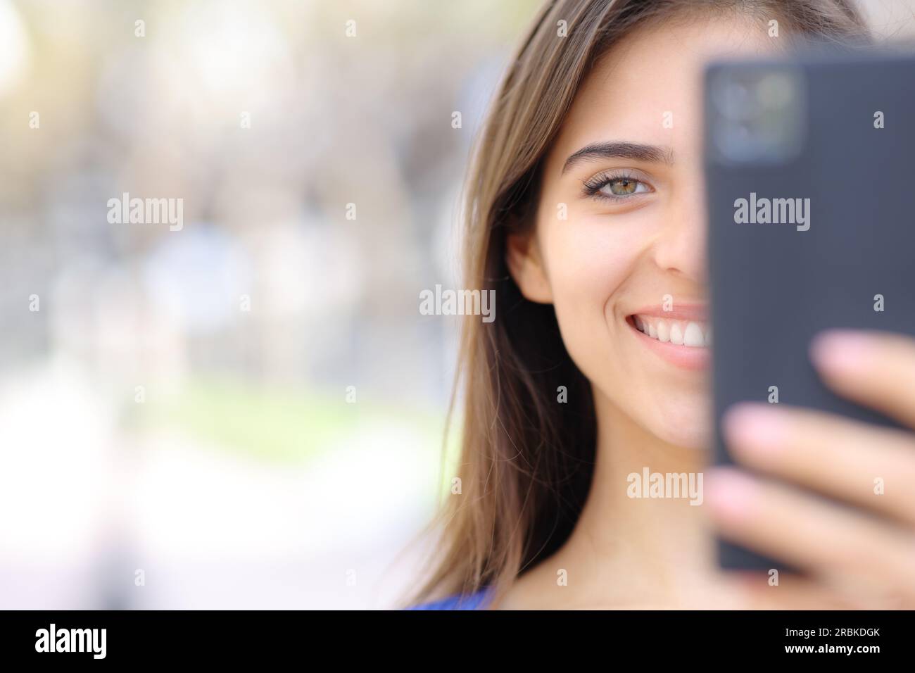 Primo piano del ritratto di una donna felice che usa il telefono cellulare con spazio per le copie che ti guarda Foto Stock