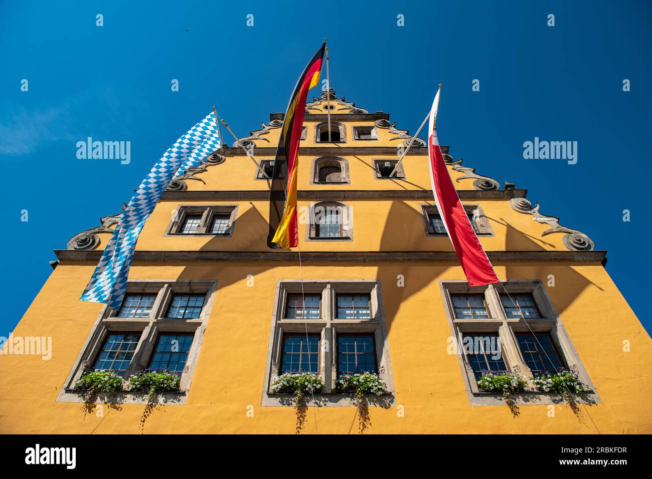 Bandiere appendono da un edificio giallo nella città vecchia, Dinkelsbuehl, Franconia, Baviera, Germania, Europa Foto Stock