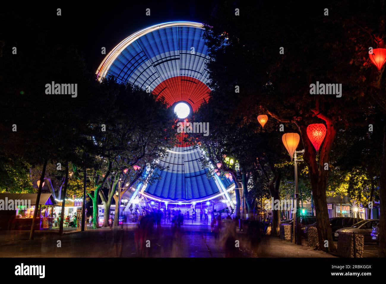 Ripresa notturna di una ruota panoramica illuminata con colori francesi, Béziers, Hérault, Francia, Europa Foto Stock