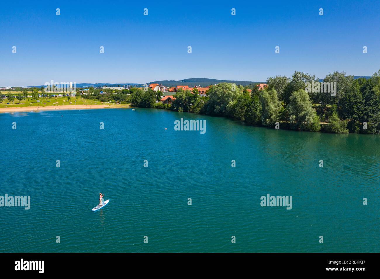 Veduta aerea di una donna che salta da una tavola da paddle SUP a Badsee, Niedernberg, Spessart-Mainland, Baviera, Germania, Europa Foto Stock