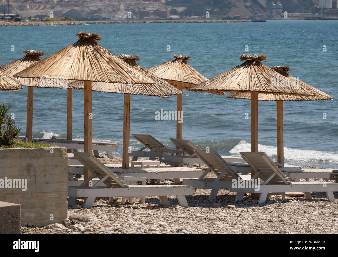 Stagione turistica. Posti a sedere vuoti sulla spiaggia sotto un ombrellone. Il mare senza persone sullo sfondo Foto Stock