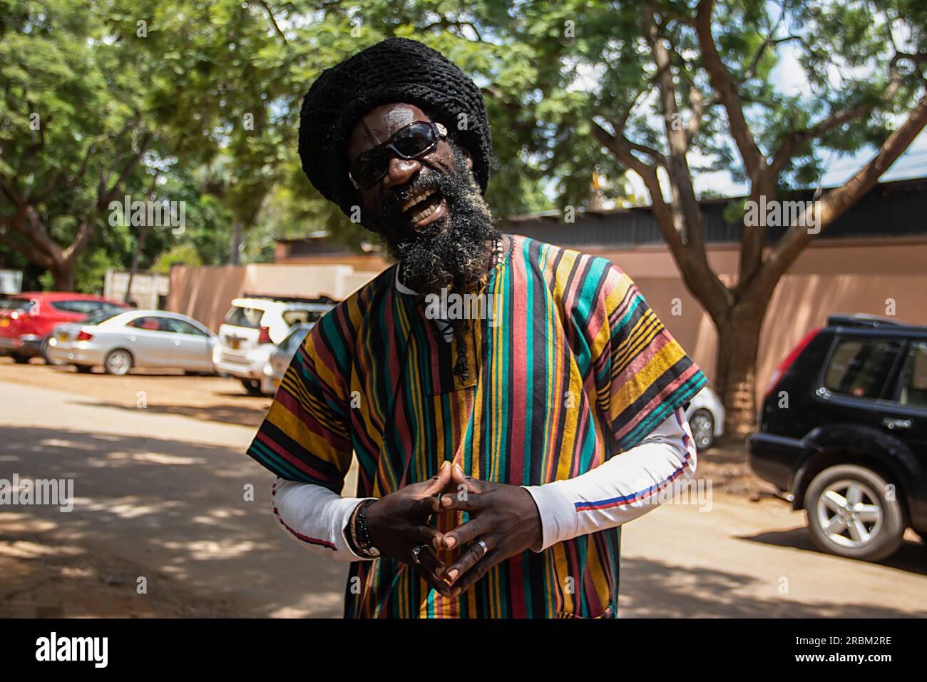 Felice Rastafari che indossa abiti colorati e cappello di lana, con dreadlock e un modo di pensare positivo, anello di pace al dito Foto Stock