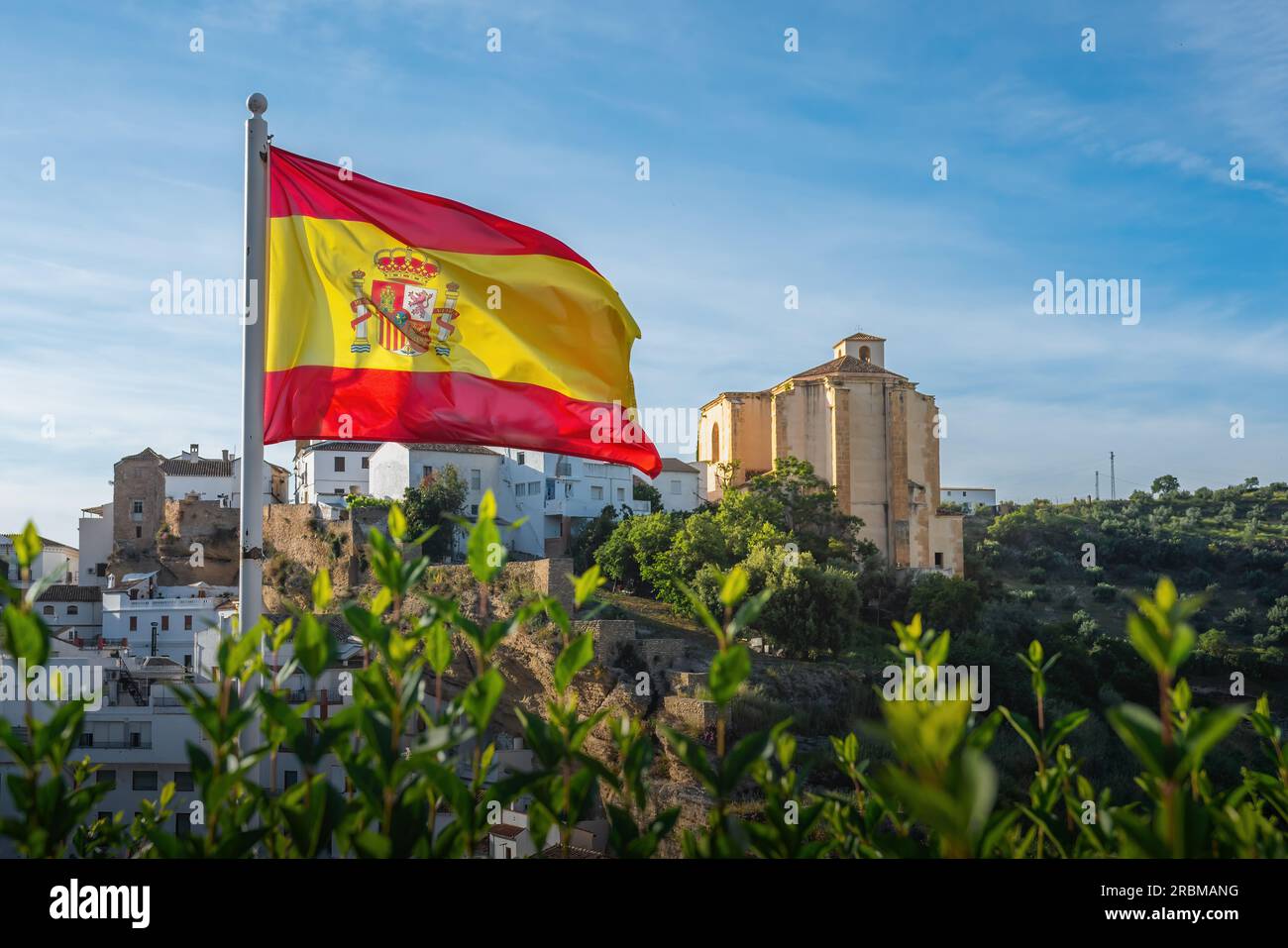 Bandiera di Spagna e Chiesa di la Encarnacion - Setenil de las Bodegas, Andalusia, Spagna Foto Stock