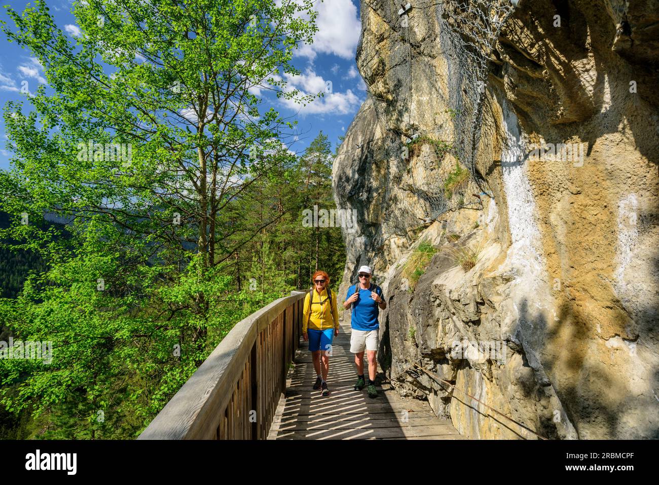 Uomo e donna che camminano lungo la parete rocciosa sulle Alpi Starkenberger Weg, Starkenberger Weg, via Claudia Augusta, Fernpass, Lechtal, Tirolo, Austria Foto Stock