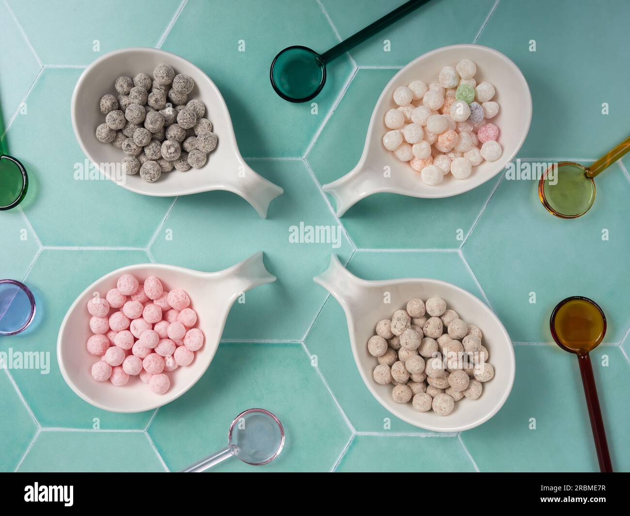 Palline di tapioca crude e crude con diversi sapori, note anche come boba in bubble tea, su sfondo piastrellato verde. Un ingrediente per preparare il tè al latte perlato. Foto Stock