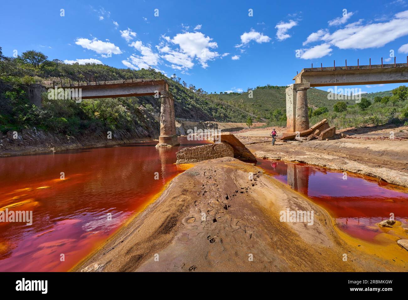 Una donna simpatica in bici elettrica in un tour in bicicletta lungo il fiume Rio Tinto con le sue acque rosse naturali in Andalusia, Spagna Foto Stock