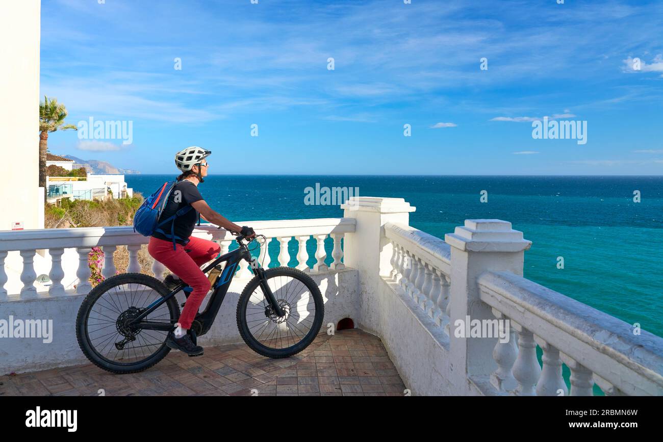 Una bella donna anziana in bicicletta con la sua mountain bike elettrica sulla costa della Costa Blanca vicino a Nerja, Andalusia, Spagna Foto Stock