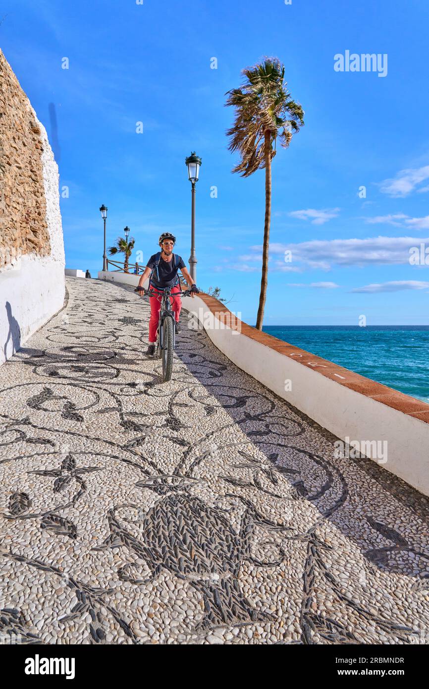 Una bella donna anziana in bicicletta con la sua mountain bike elettrica sulla costa della Costa Blanca vicino a Nerja, Andalusia, Spagna Foto Stock