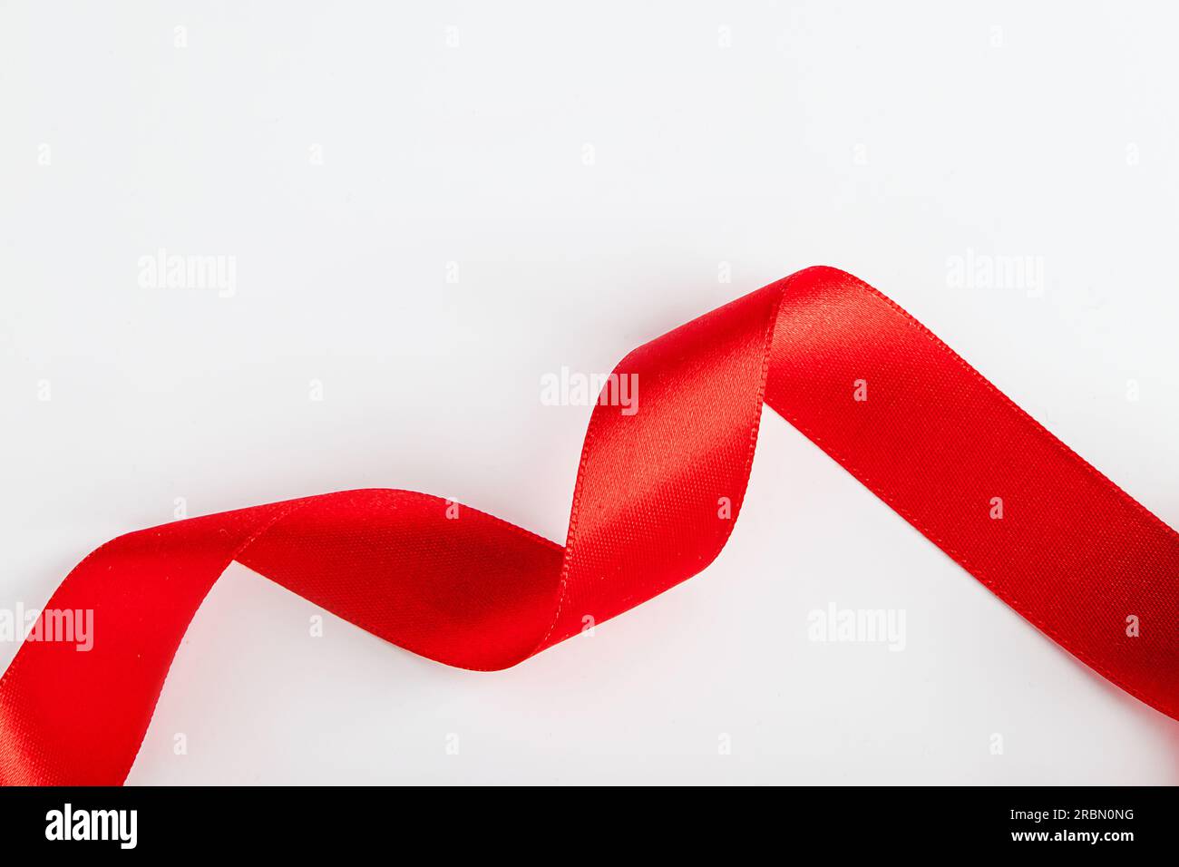 Nastro di seta rossa per l'imballaggio dei regali su sfondo bianco. Ricci di nastro decorativo per le vacanze. Elemento per il design. Foto Stock