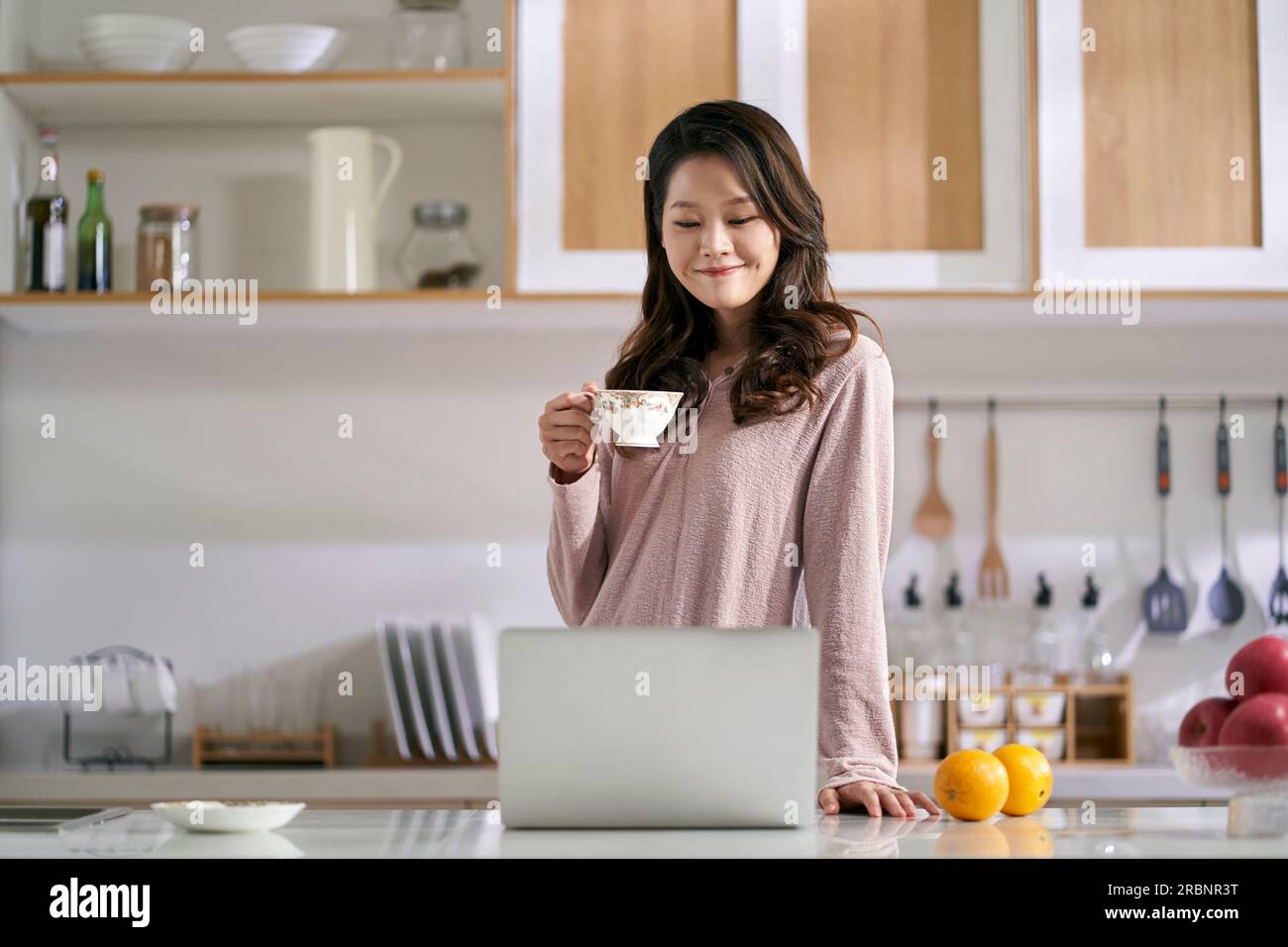 giovane donna d'affari asiatica che lavora in cucina a casa utilizzando un computer portatile Foto Stock