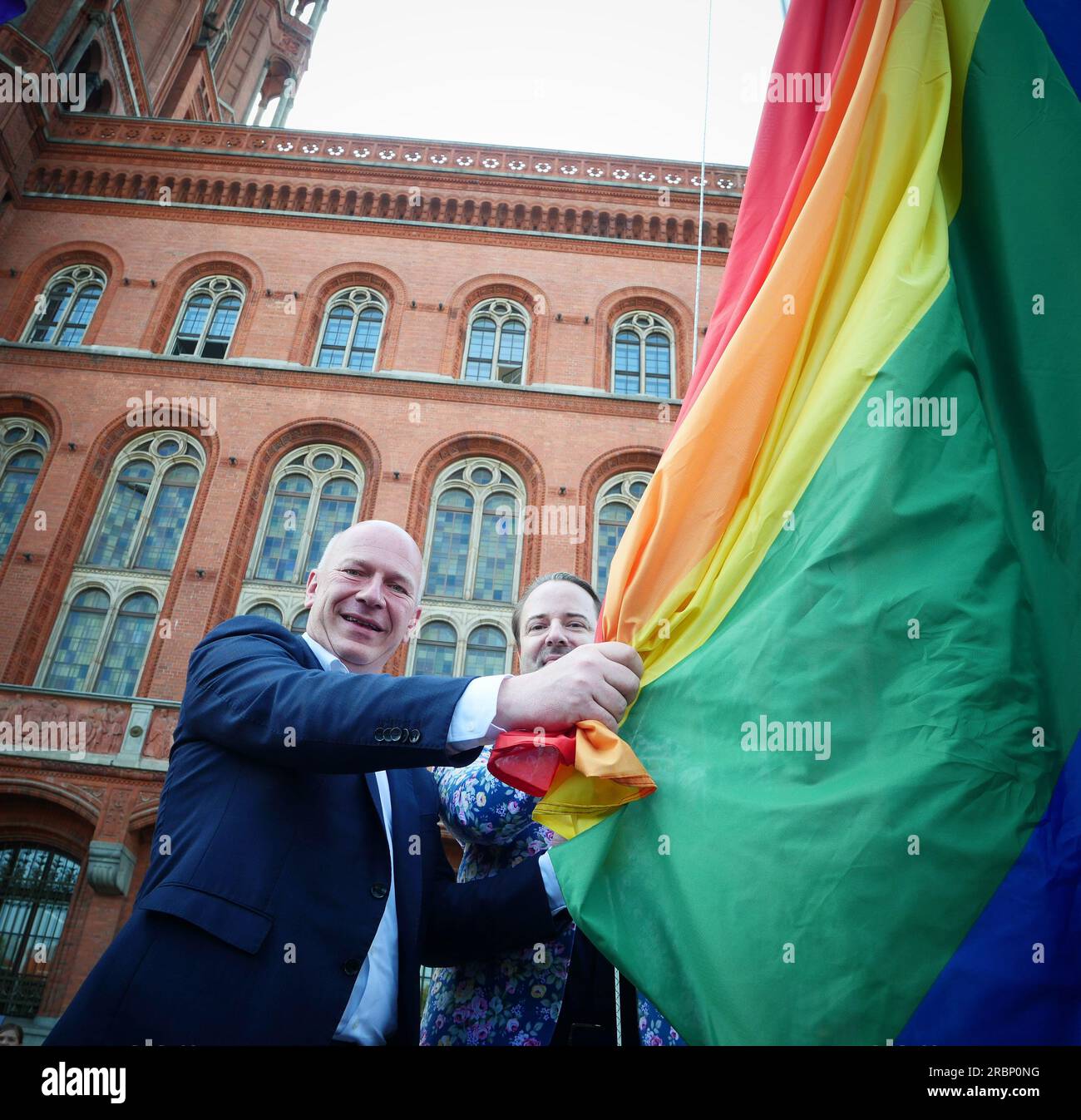 Berlino, Germania. 10 luglio 2023. Il sindaco di Berlino, Kai Wegner (l, CDU) e Alexander Scheid di LSVD alzano la bandiera arcobaleno di fronte al Municipio Rosso di Berlino-Mitte. Questo segnò l'apertura ufficiale di Pride Weeks. Credito: XAMAX/dpa/Alamy Live News Foto Stock