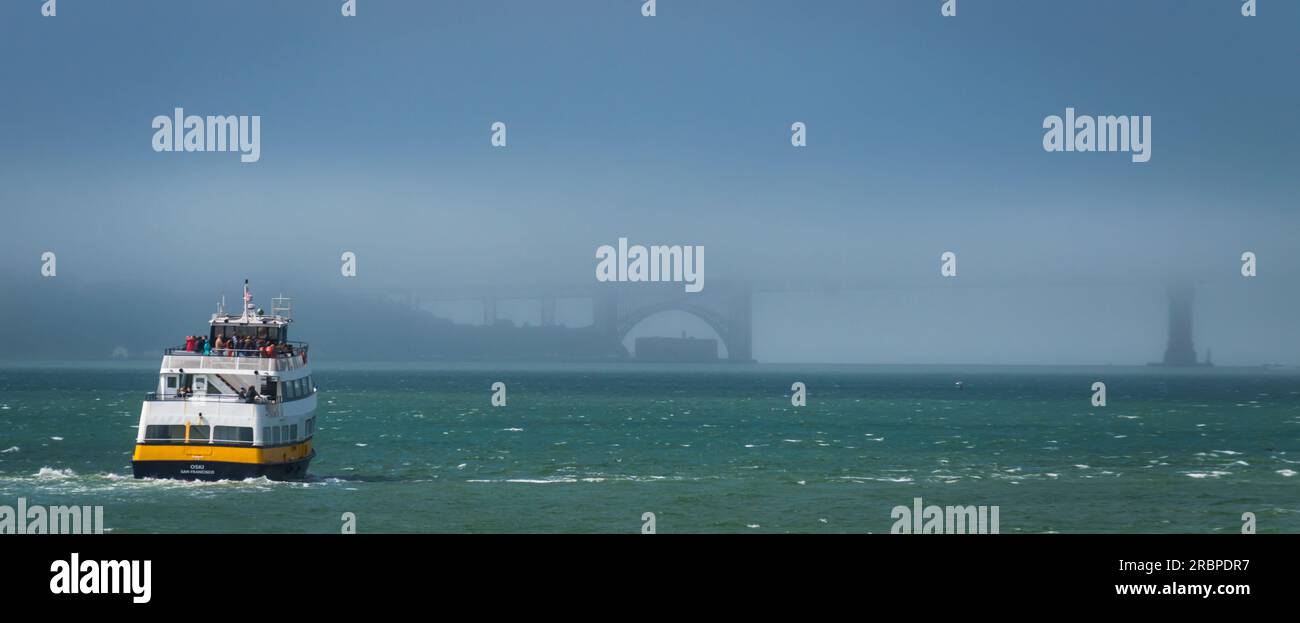 Un piccolo traghetto sta andando verso il Golden Gate Bridge nella nebbia di San Francisco, California Foto Stock