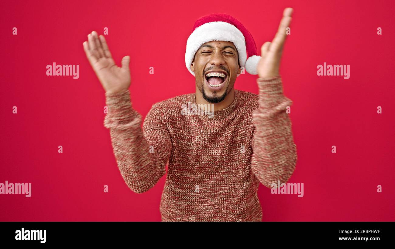 Uomo afro-americano che indossa un cappello di natale applauso con le mani  e applausi su sfondo rosso isolato Foto stock - Alamy